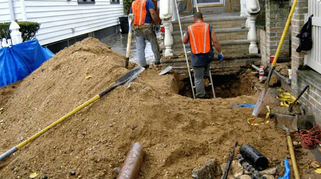 Contractors performing foundation protection and exterior drainage excavation near residential home steps in Anaheim, CA
