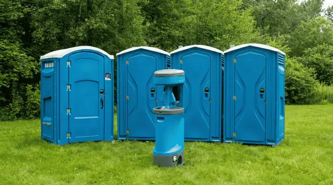 Four blue portable toilets and a matching hand washing station on grass near trees, a common sight at local outdoor events in Anaheim, CA